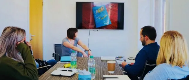 a group of people in a meeting room looking at a screen